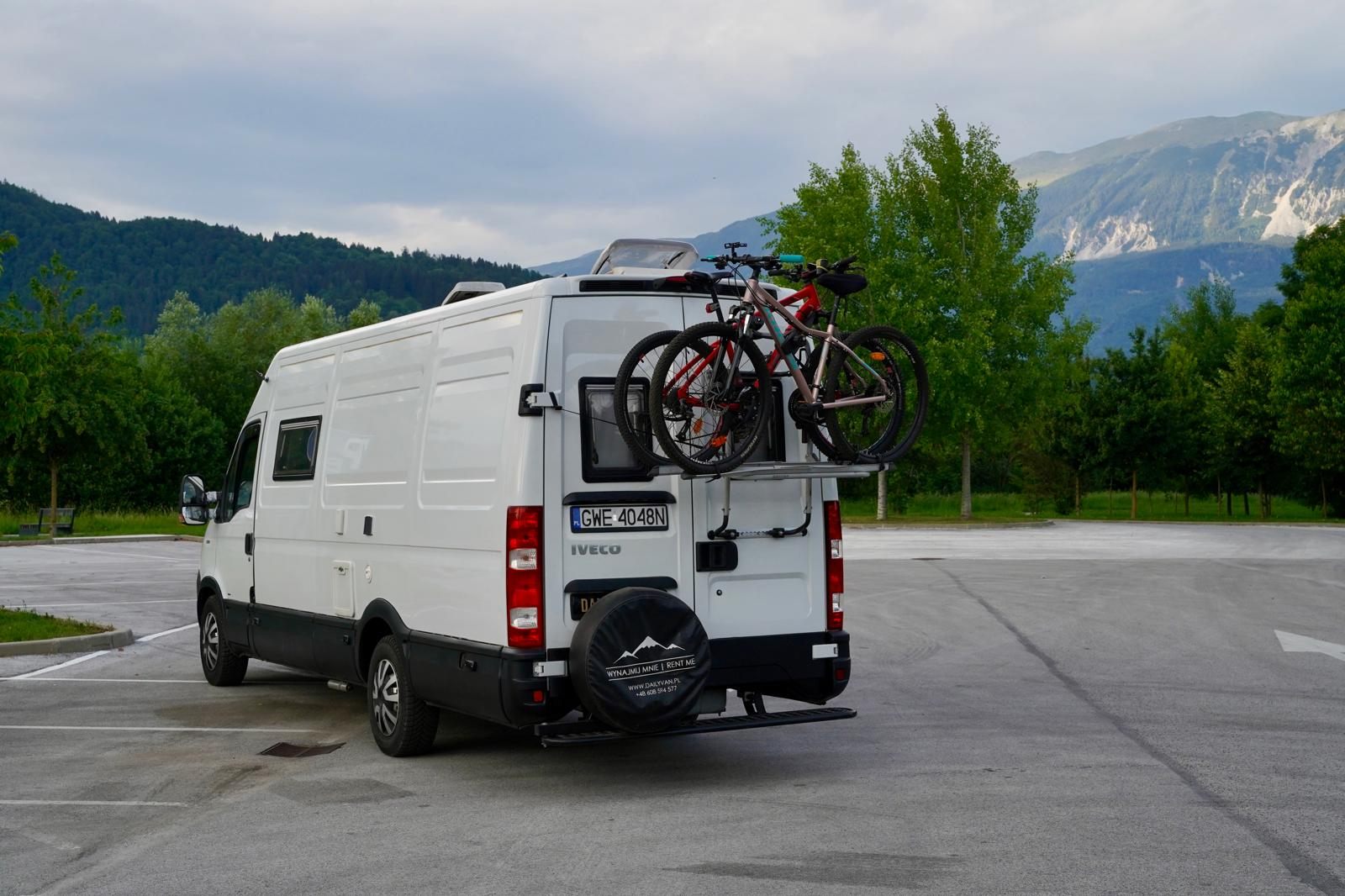 Iveco Daily tyłem z bagażnikiem rowerowym, w tle alpejskie szczyty