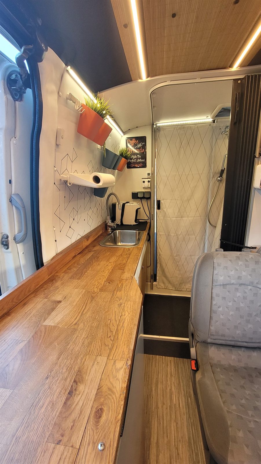 Wnętrze Iveco Daily — drewniana podłoga i zabudowa, przejście w głąb kampera